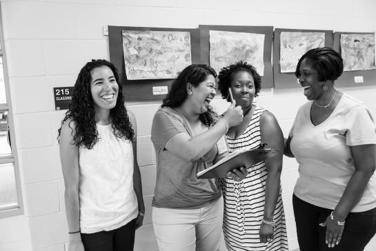 group of educators talking and laughing in school hallway