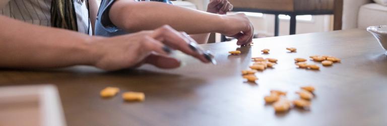 Woman working with young boy with disabilities sorting Goldfish crackers