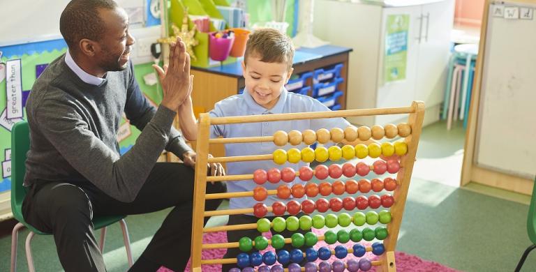 Young male teacher giving young male student a high-five while doing visual math problem