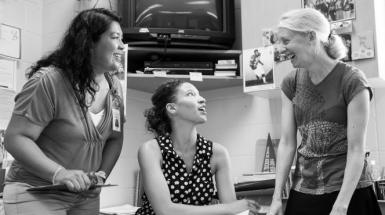 3 teachers collaborating and talking around desk