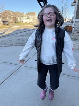 child jumping for joy in a driveway