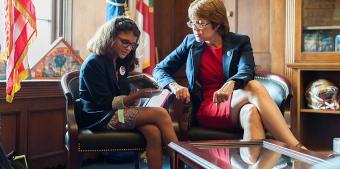 Senator speaking with child in Congressional office looking at assistive technology device