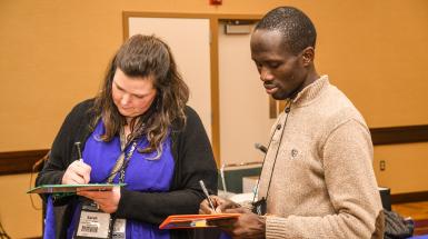 Man and woman standing and taking notes 